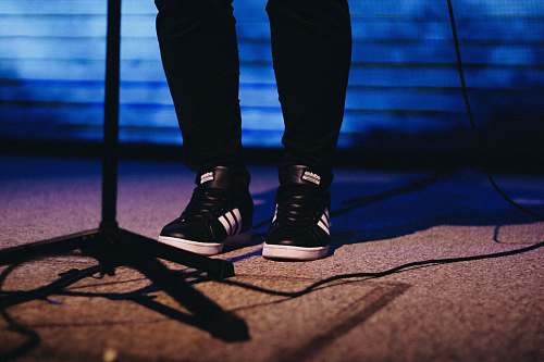 brazil person showing pair of black-and-white adidas shoes heel